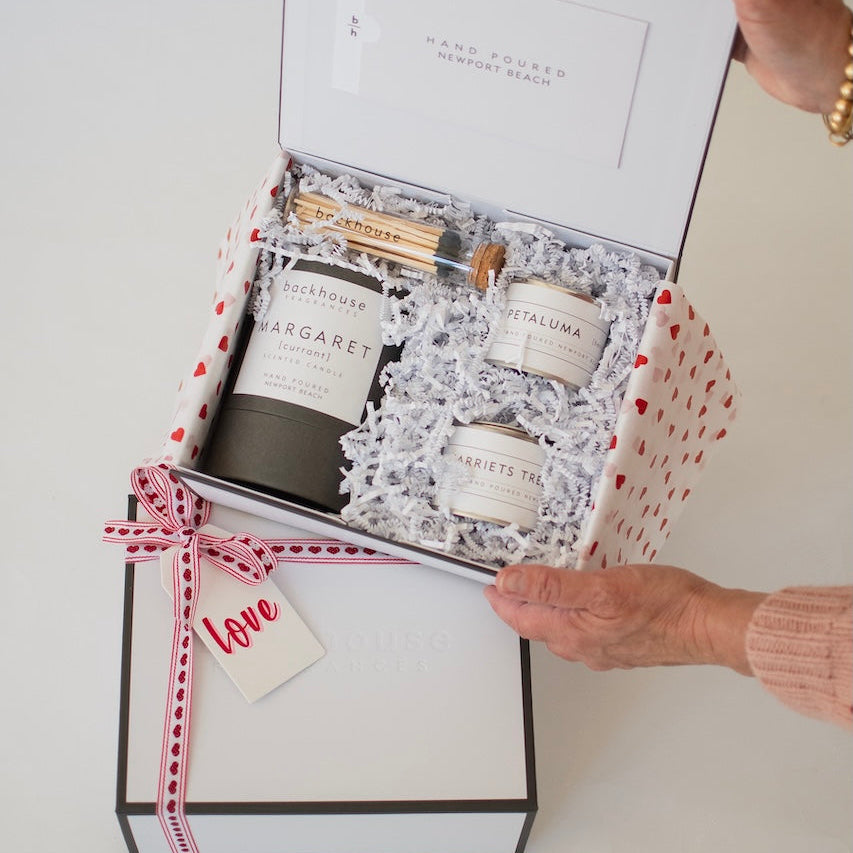 Gift set with candles and a in a Valentine's box on a white surface.