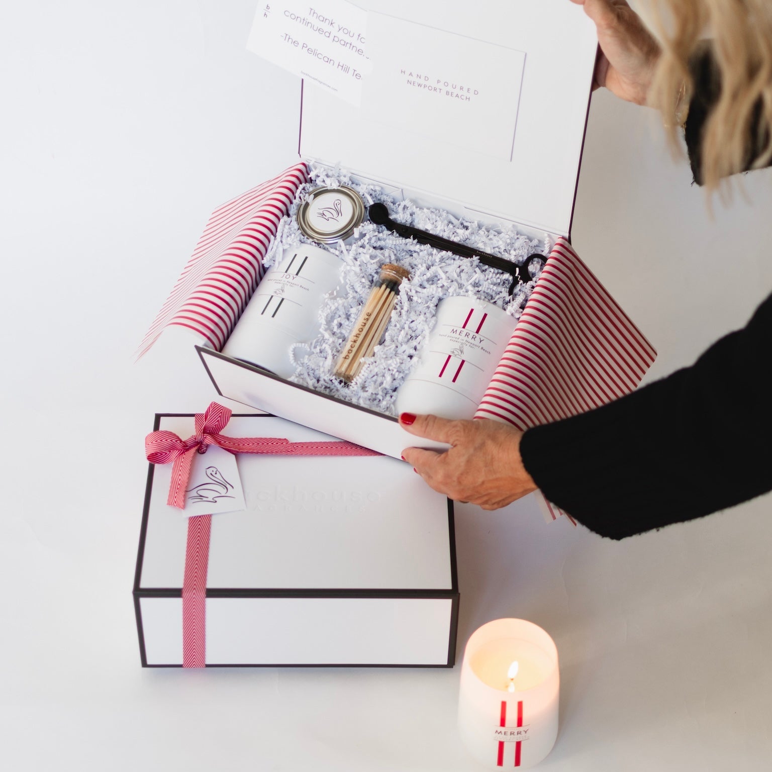 person holding gift box showing contents inside - candles