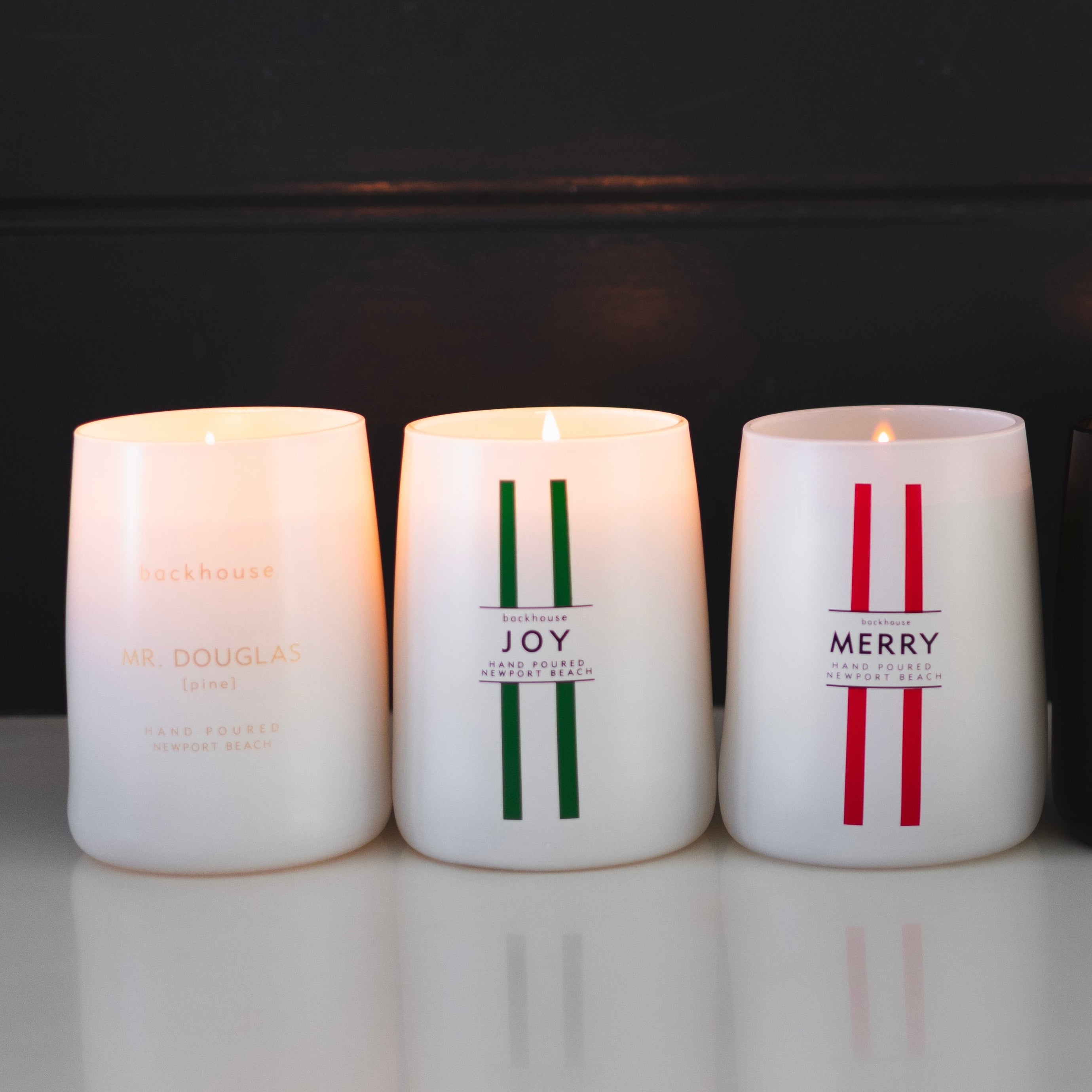 Five candles with decorative text on a reflective surface and dark background