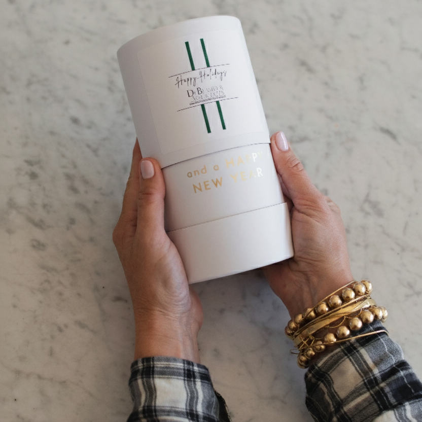 Person holding two cylindrical product containers with text on a marble surface. custom corporate cylinder box for a scented candle.