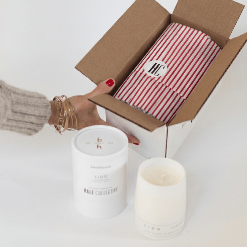 Open backhouse box with striped red and white tissue paper, corporate gifting candle with custom cylinder box sticker
