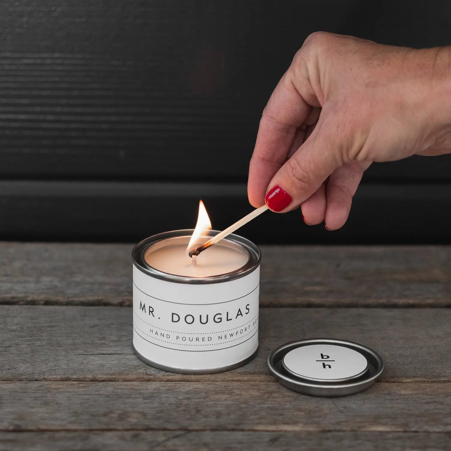 Mini Mr. Douglas pine candle by backhouse burning against a dark background in its classic glass vessel.