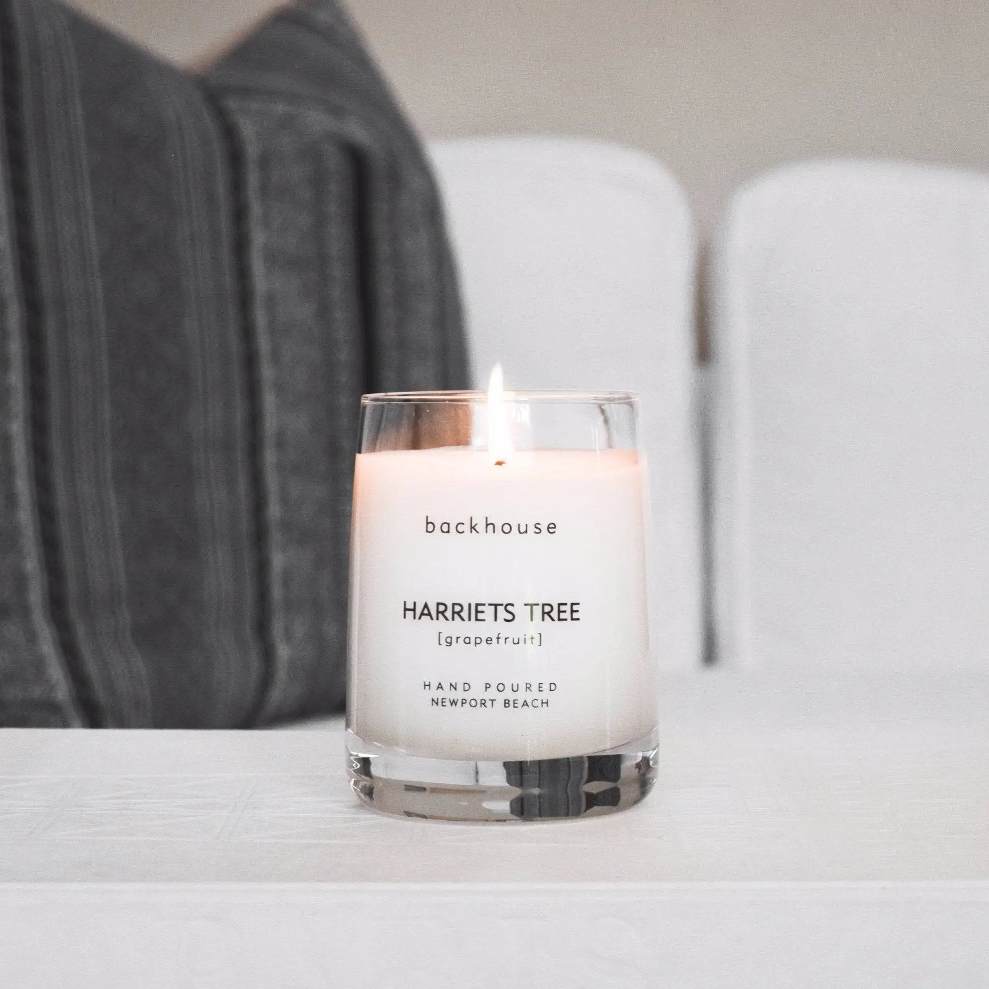 Harriets Tree grapefruit hurricane candle by backhouse burning on a coffee table. Newport Beach