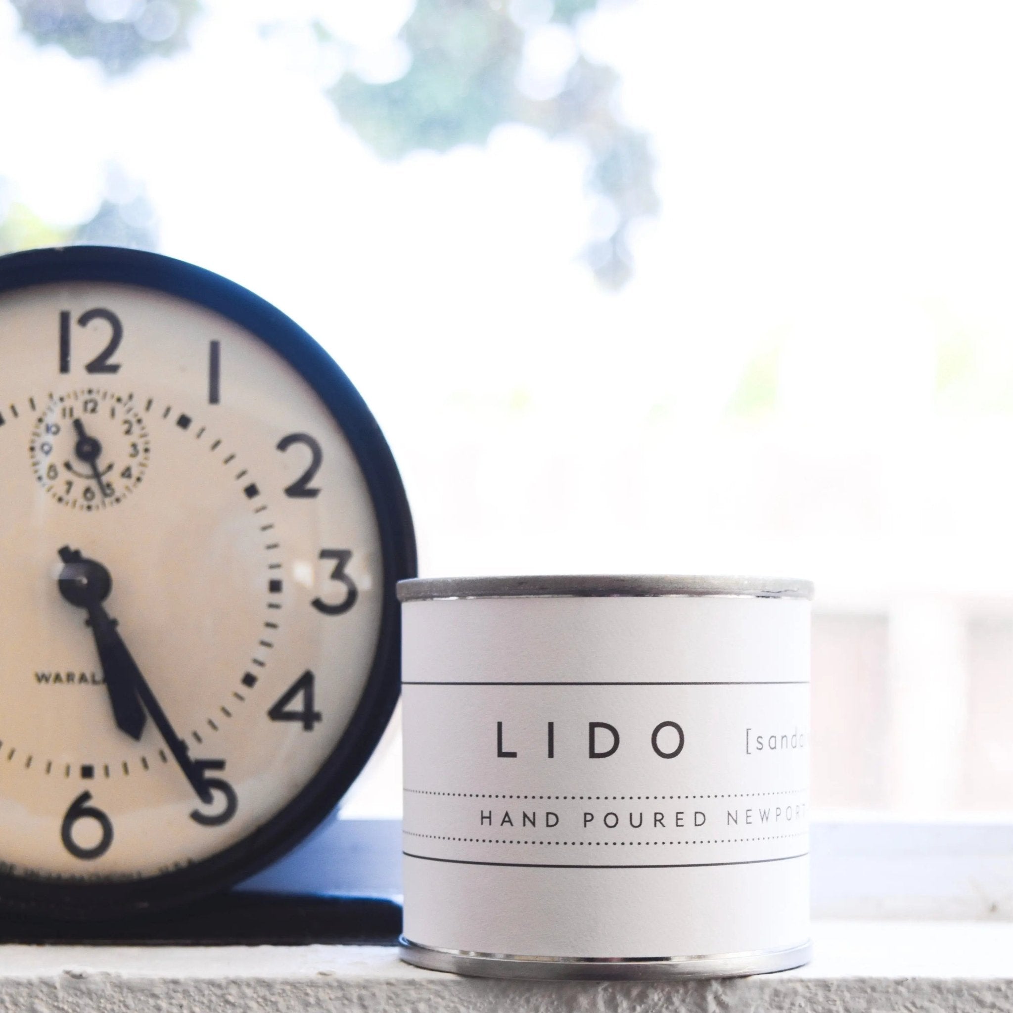 Mini Lido sandalwood candle by backhouse displayed beside a clock on a styled surface.