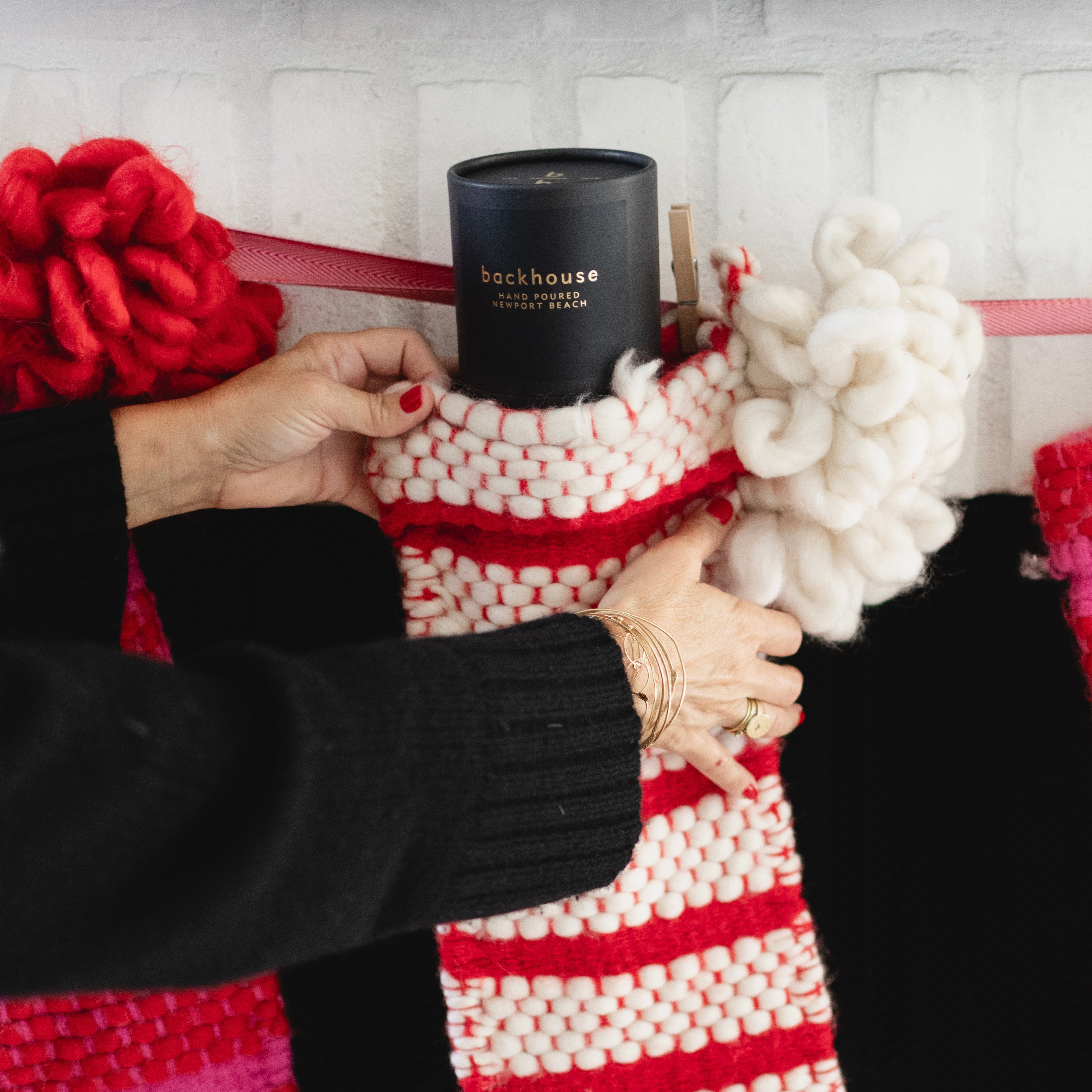 Person placing a black candle inside a red and white striped stocking.