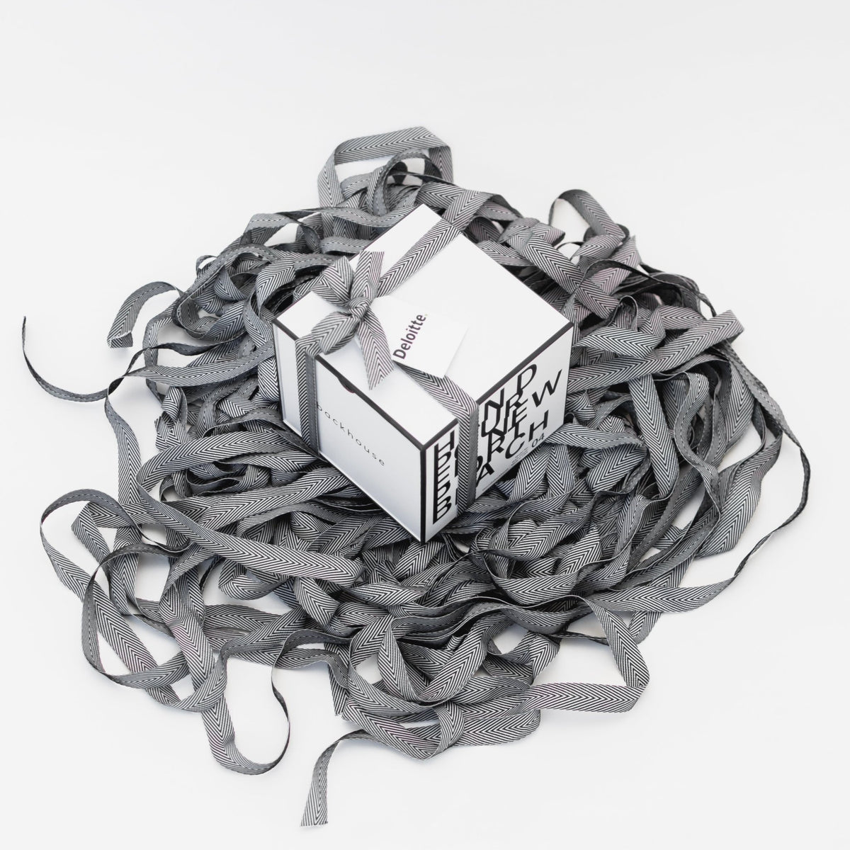 Backhouse Fragrances Deloitte branded corporate gift box tied with herringbone ribbon, nestled in a pool of signature ribbon on white background