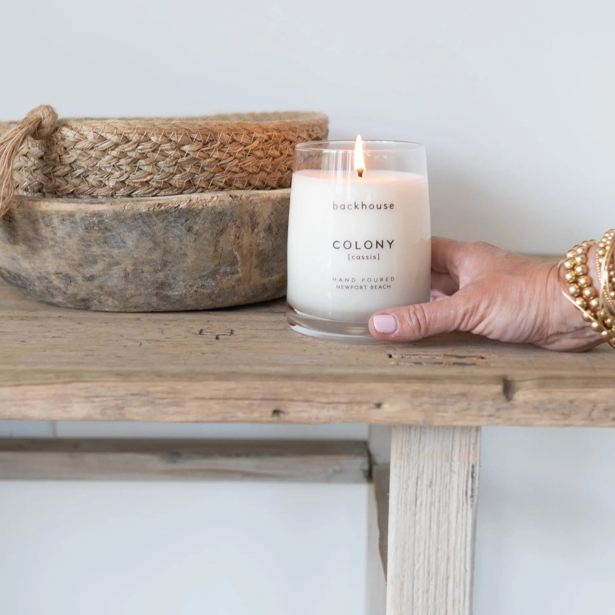 Colony cassis candle by backhouse Fragrances burning on a shelf in a neutral interior setting. Newport Beach. Gifting Made Easy 