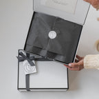 Backhouse Fragrances corporate gift box with Thomas James Homes branded tag and herringbone ribbon being opened