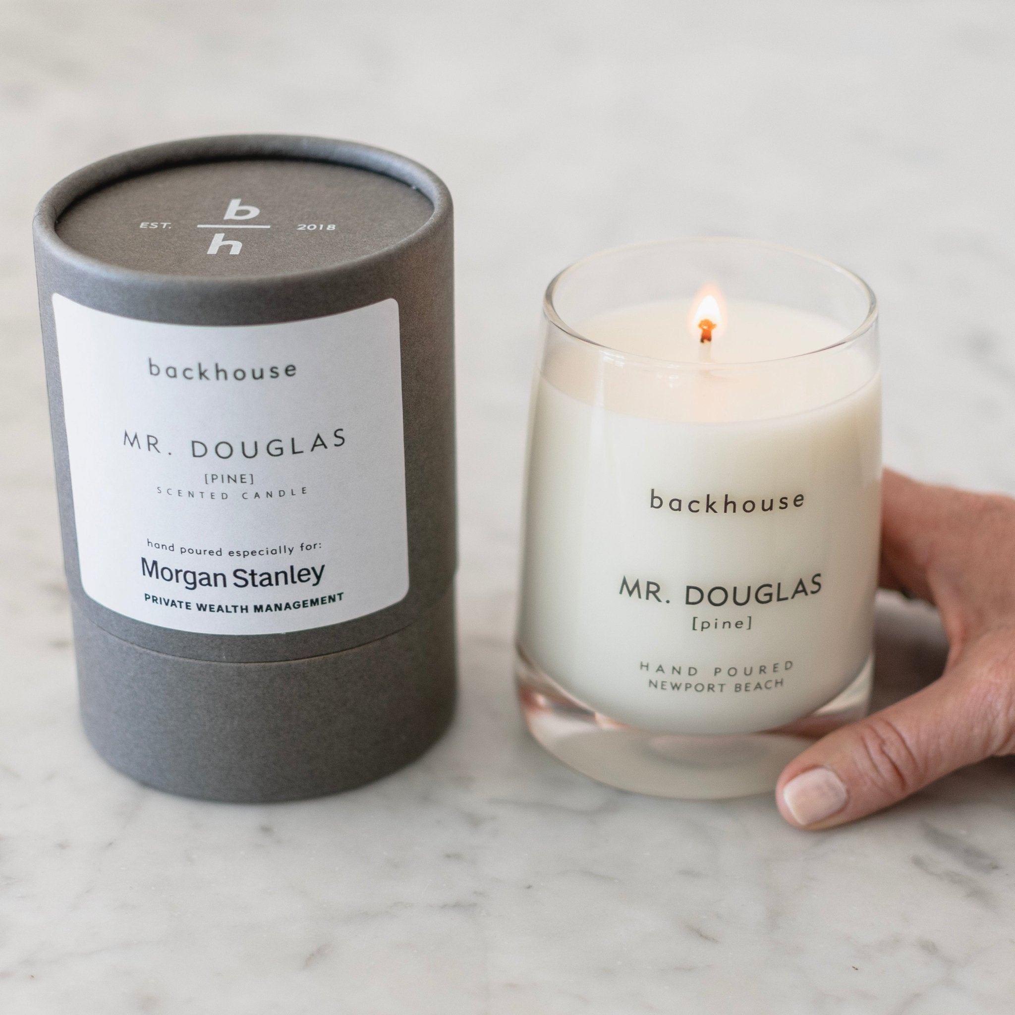 Backhouse Mr. Douglas pine candle hand poured for Morgan Stanley Private Wealth Management, lit on a marble surface