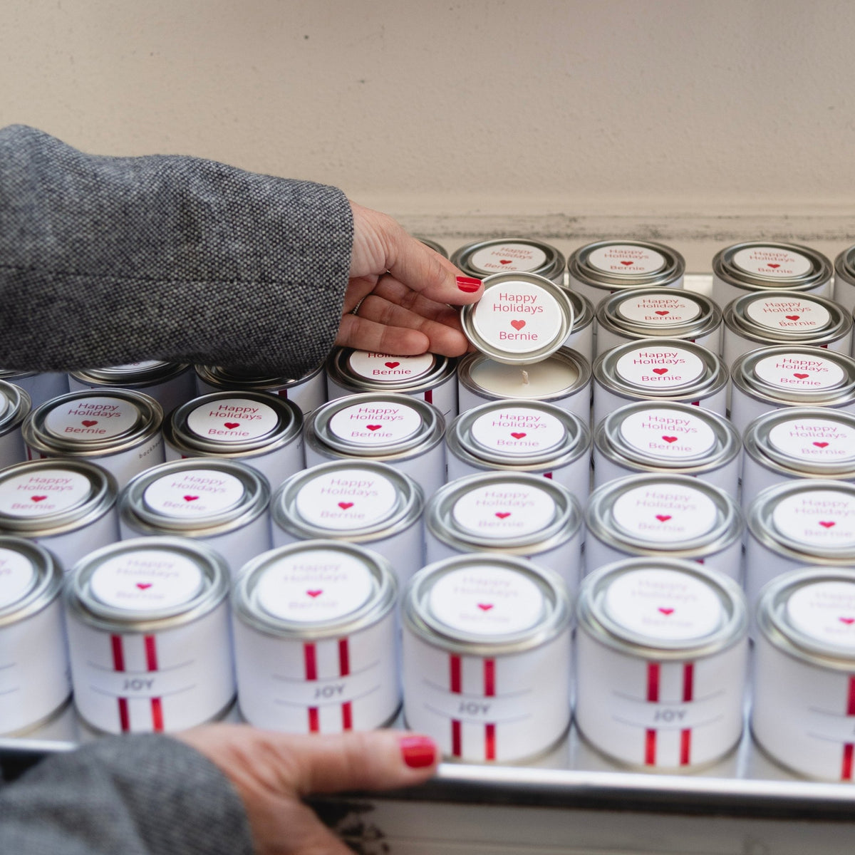 Hands showing a Backhouse candle with custom happy holidays top at a work table in the Newport Beach studio