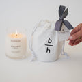 Backhouse Colony cassis candle lit beside a branded canvas bag with Tradition Title Company corporate gift tag and herringbone ribbon
