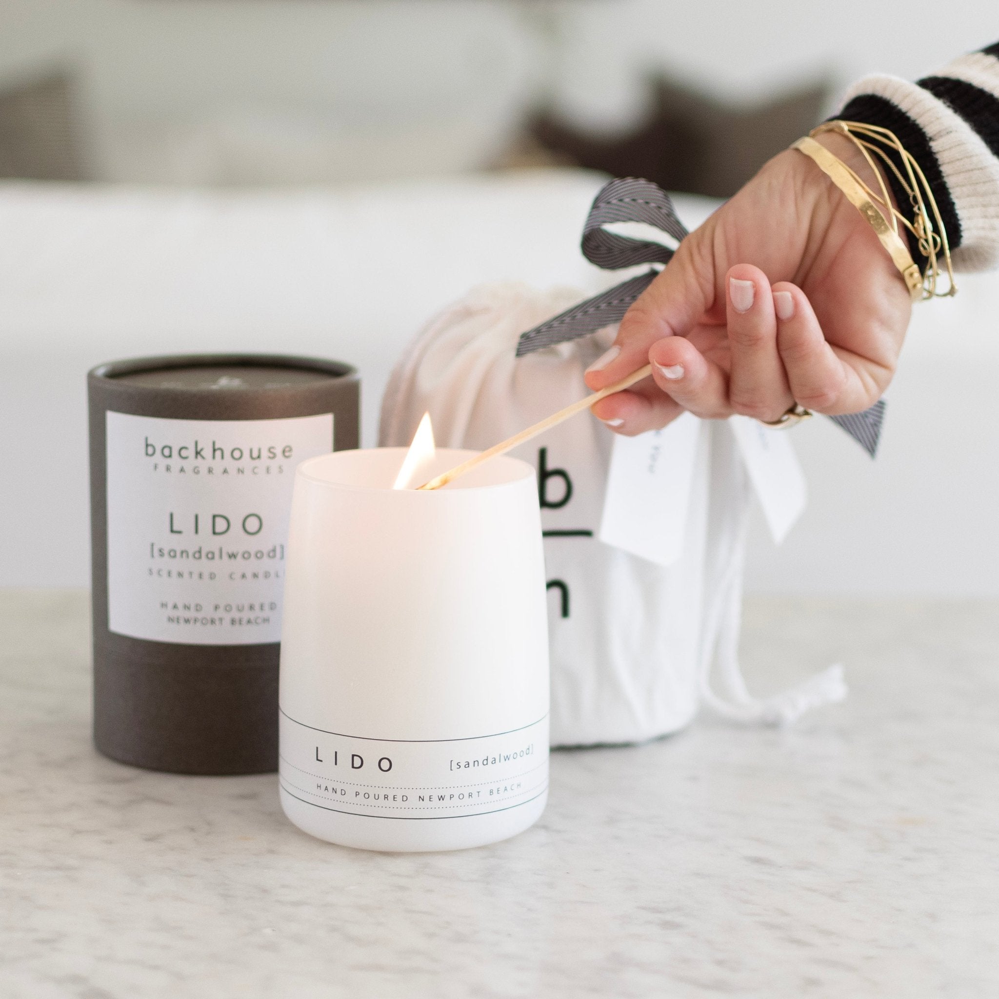 Lighting Backhouse Fragrances Lido sandalwood scented candle beside kraft gift packaging and branded gift bag, hand-poured luxury candle Newport Beach
