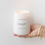 Hand holding lit Backhouse Fragrances Margaret currant scented candle, hand-poured luxury home fragrance in Newport Beach California