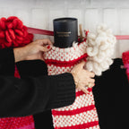 Person placing a black candle inside a red and white striped stocking.