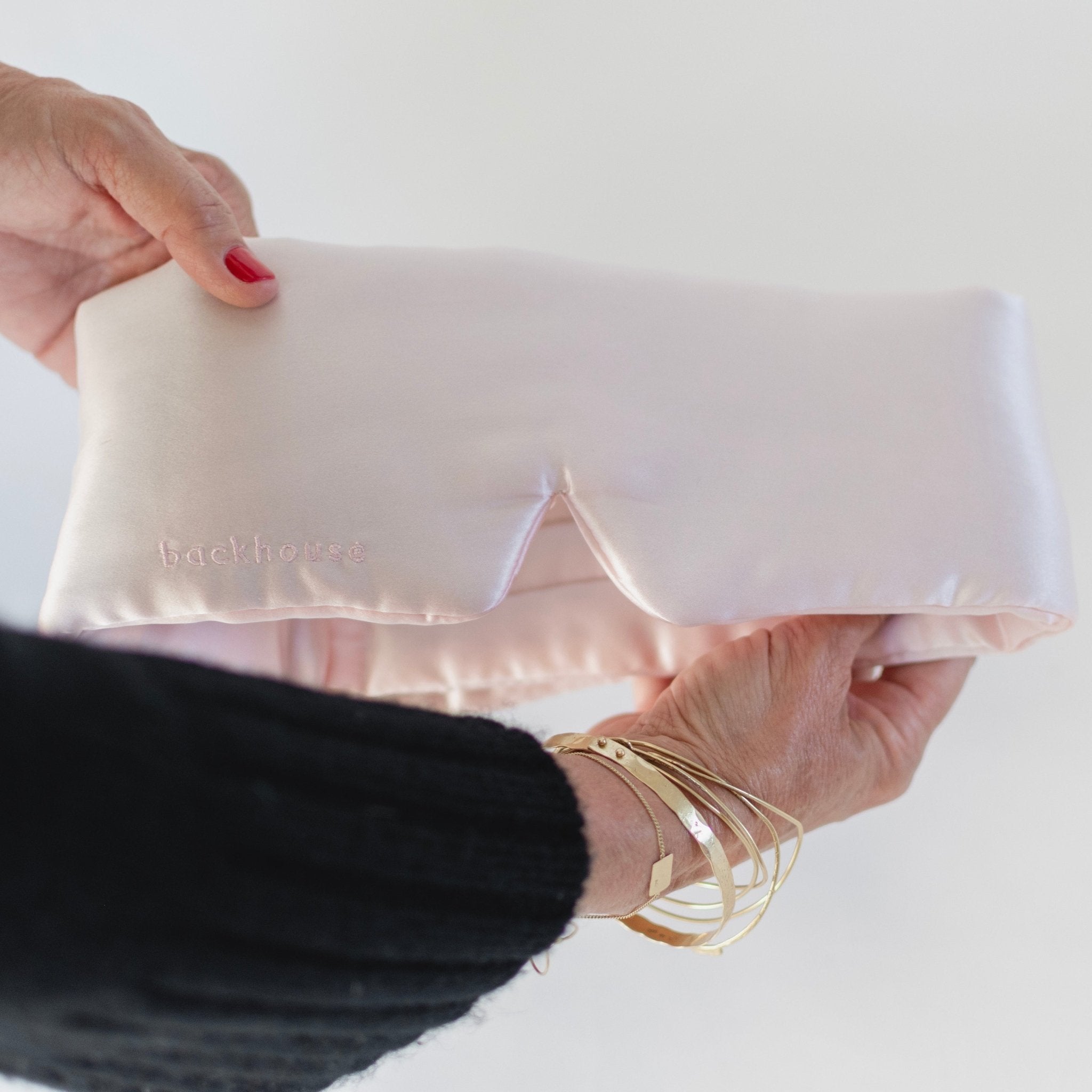 Person holiding a pink silk eye mask 