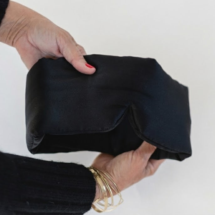 Person holding a black eye mask item on a white background