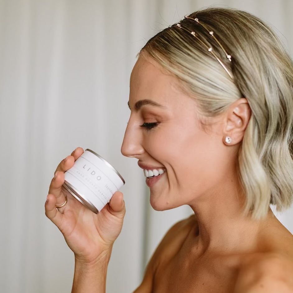 Close-up of a bride smelling a sandalwood scented Newport Beach custom hand-poured mini candle wedding favor with a personalized label.