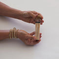 Hands holding a glass tube of matches by backhouse against a white background.