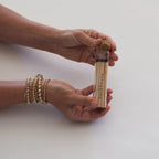 Hands holding a glass tube of matches by backhouse against a white background.