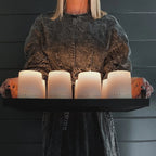 Multiple Jack pumpkin candles by backhouse lit and held in hand against a dark background.