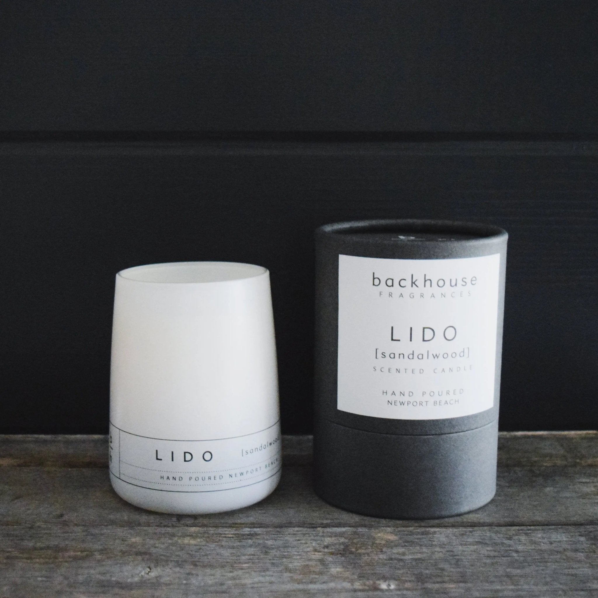 Lido sandalwood hurricane candle by backhouse displayed beside its signature cylinder box against a dark background.
