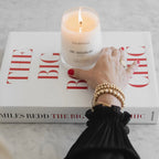 Mr. Douglas pine candle by backhouse burning on a red and white coffee table book.